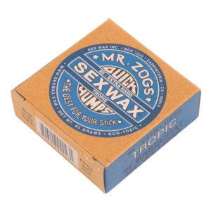Shapers-Club- Une boîte marron et bleue de Sexwax - Tropic Basecoat de Mr. Zog, étiquetée « Quick Humps Tropic » et « The Best for Your Stick ». La boîte indique qu'elle est extra dure, non toxique et pèse 85 grammes. Idéal comme couche de base pour votre planche. -surfshop-surfboard